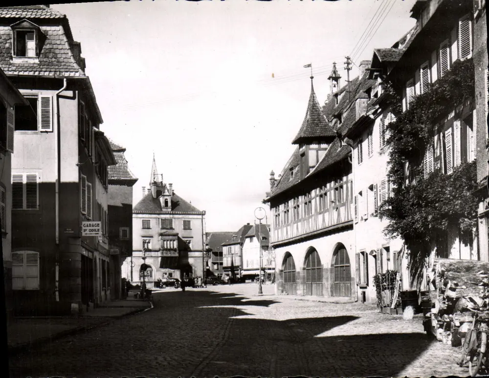Obernai - Rue du Marché — vista da rua com edifícios com colmios e garagem — Edição La Cigogne, Strasbourg - Frente