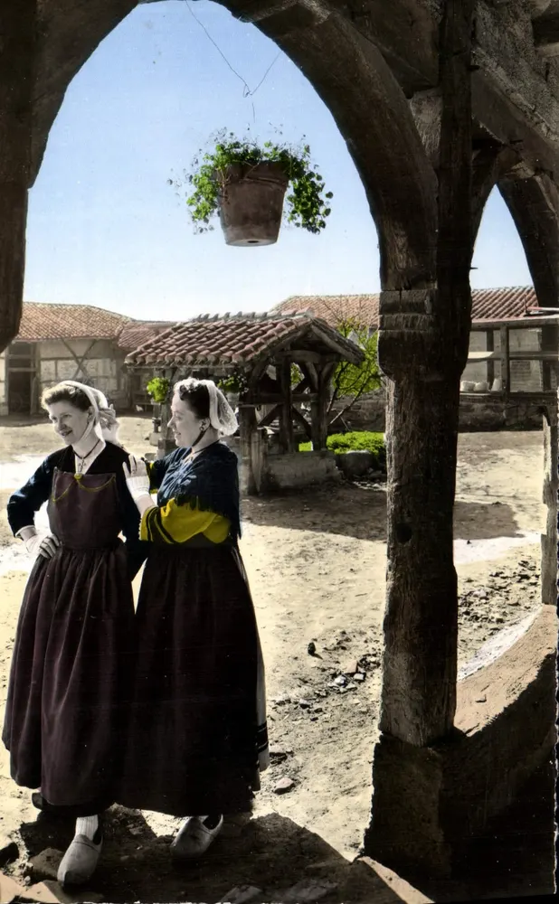 Deux femmes en costume traditionnel — sous un porche en bois — Éditions ALLAIN, Lyon - Recto