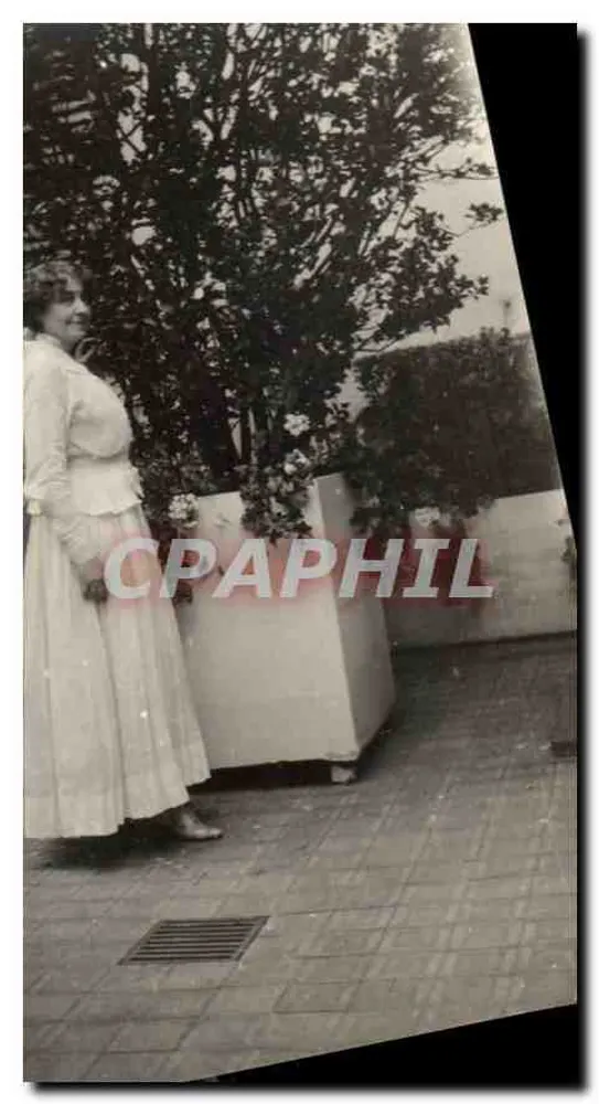 Mulher em vestido longo — jardim ou balcão — sem editor ou número visível - Frente