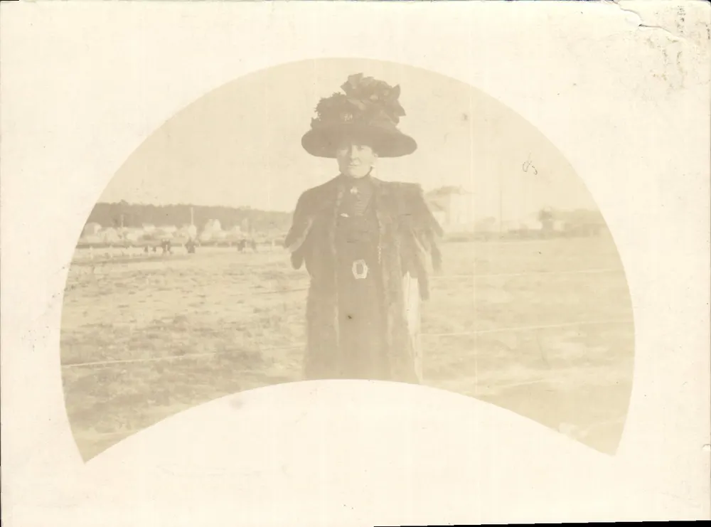 Femme en manteau fourré et chapeau décoré — scène champêtre avec personnes à l'horizon — éditeur non visible - Voorkant
