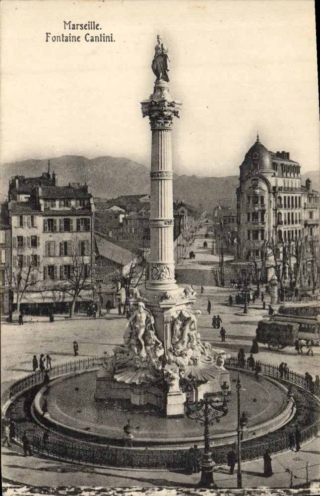 Marselha. Fonte Cantini. — Vista da fonte monumental com coluna e estátuas, no centro de uma praça urbana. - Frente