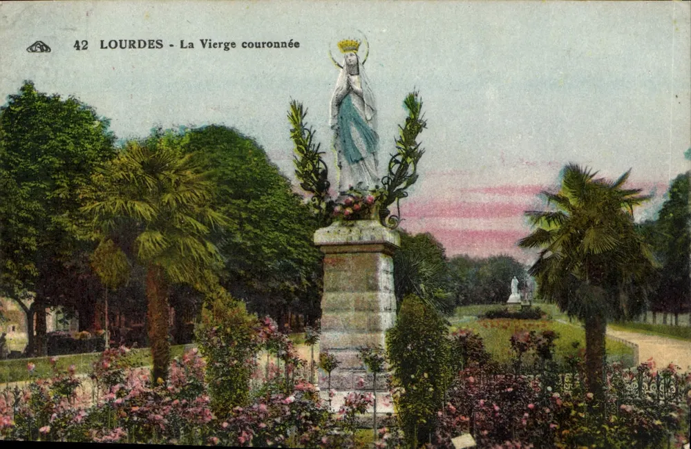 Lourdes - A Virgem coroada — estátua em um jardim com palmeiras e flores — n° 42 - Frente