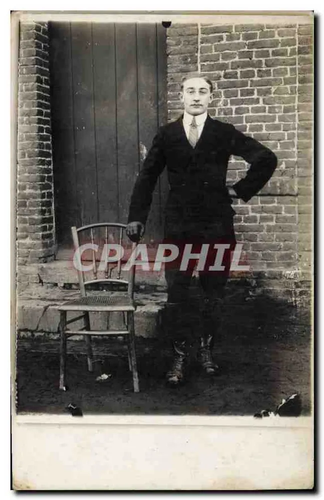 Retrato de um homem — diante de um muro de tijolos e uma porta — sem editor ou número visível - Frente
