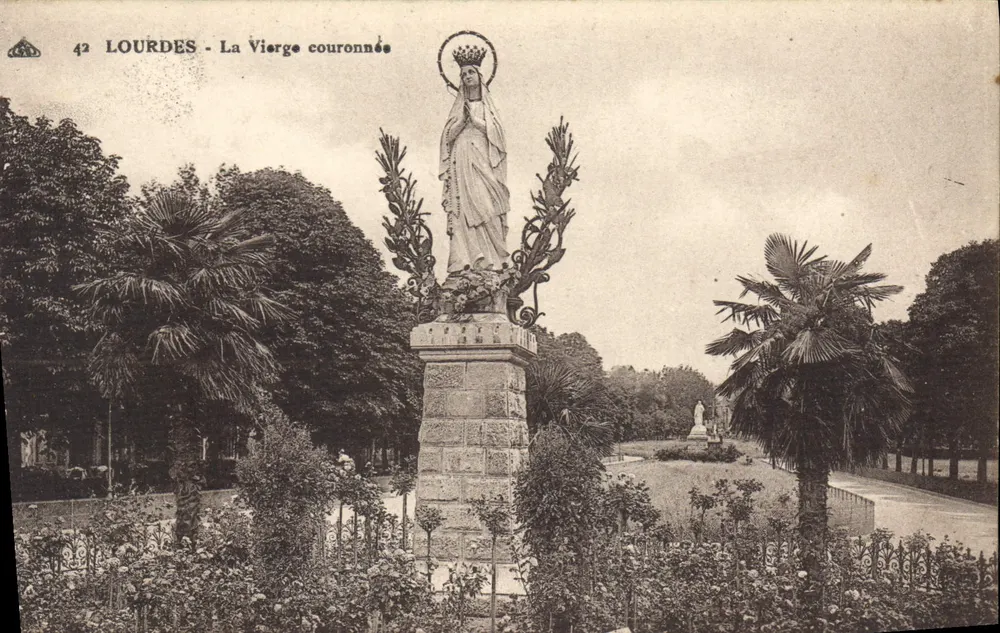 Lourdes - A Virgem Coroada — estátua sobre pedestal, palmeiras e jardim - Frente