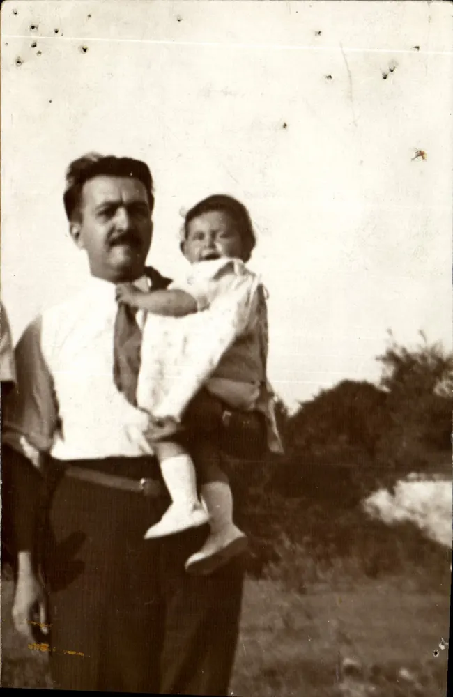 Homem segurando uma criança — cena ao ar livre — número de série não visível - Frente