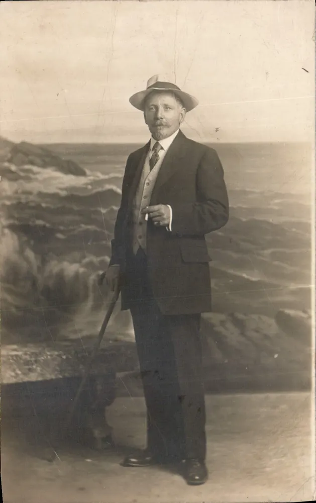 Homem com traje e chapéu — diante de paisagem marítima — Photo-Market, rua Sola-Perró, Barcelona - Frente