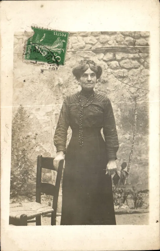 Mulher com vestido escuro — diante de uma parede de pedra — Recorrouf (Aude) - Frente