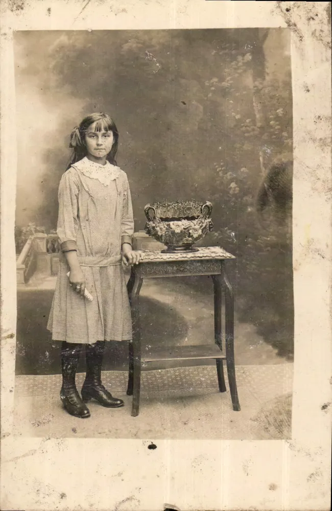 Menina com vestido de colar branco — diante de um pequeno móvel com vaso — estúdio fotográfico - Frente