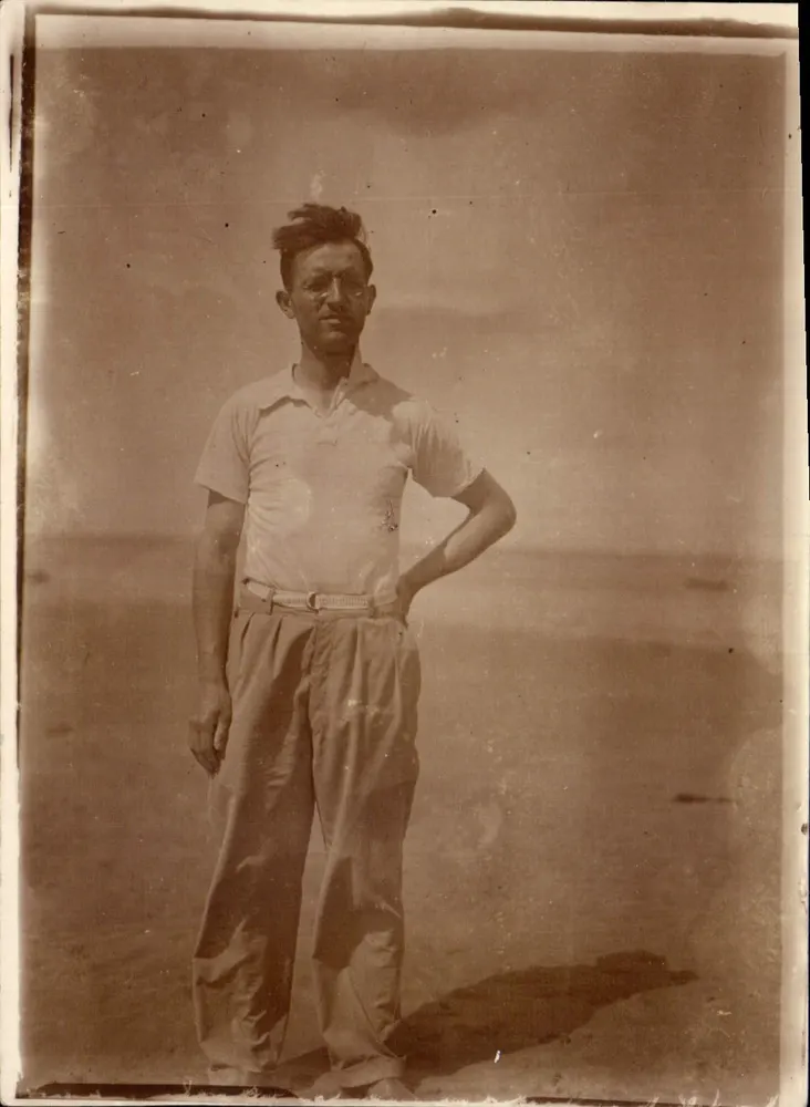 Homem em uma praia — fotografia sépia — sem editor ou número de série visíveis - Frente