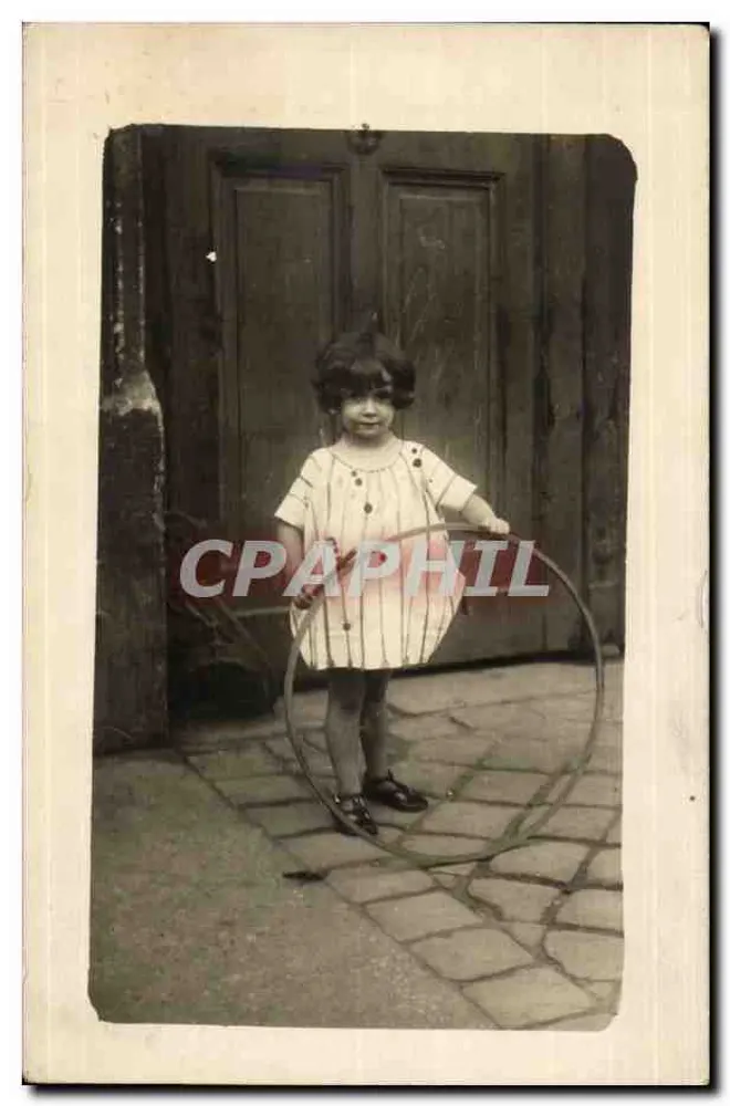 Petite fille jouant avec un cerceau — devant une porte en bois — éditeur non visible - Recto