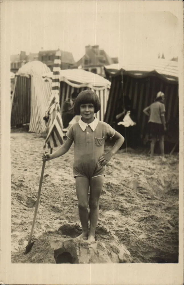 Fille en maillot de bain sur une plage — cabanes de plage en arrière-plan — éditeur non identifié - Recto