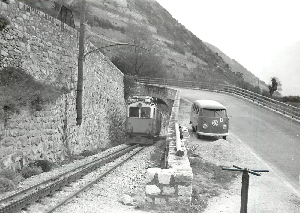 Train et Volkswagen sur route — entre Leuk-SBB et Leuk-Stadt — Photo M. Grandguillaume - Recto