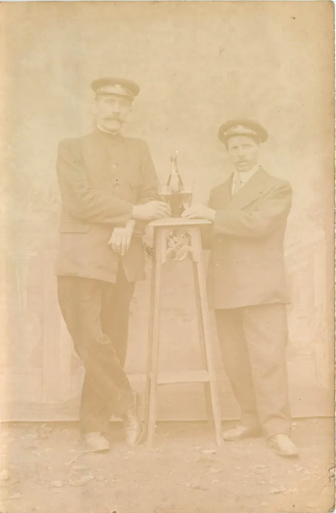 Dois homens em uniforme — pose com garrafa em pé - Frente