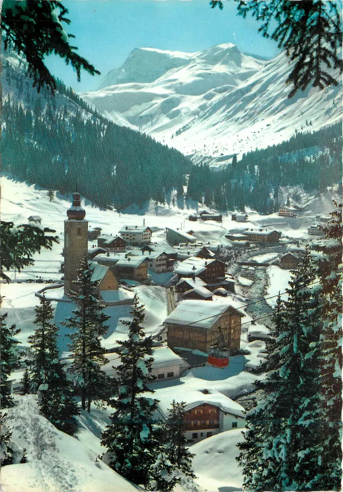 Schneeverdecktes Alpendorf — Panoramablick mit Kirche und Bergen im Hintergrund — Verleger nicht sichtbar - Vorderseite