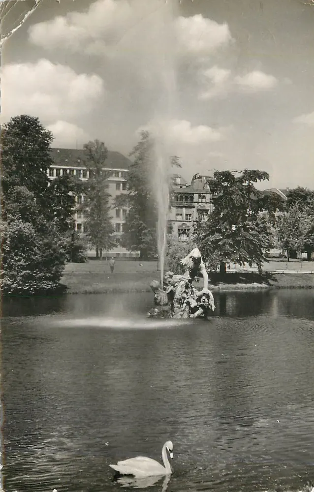 Düsseldorf a. Rh. Runder Weiher im Hofgarten — Fontaine avec cygne, éditeur Bahnhoisbuchhandlung Adam Heinz - Recto