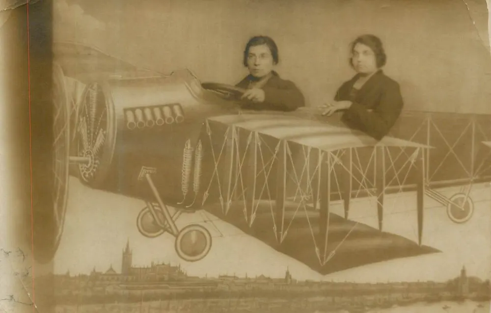 Zwei Frauen in einem Flugzeug — Blick auf eine Stadt im Hintergrund — Ansichtskarte hergestellt in England - Vorderseite