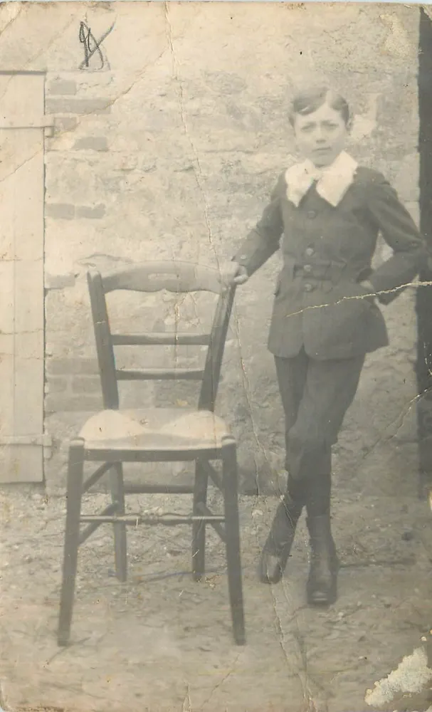 Garçon en costume — devant une chaise en bois — éditeur non visible - Awers