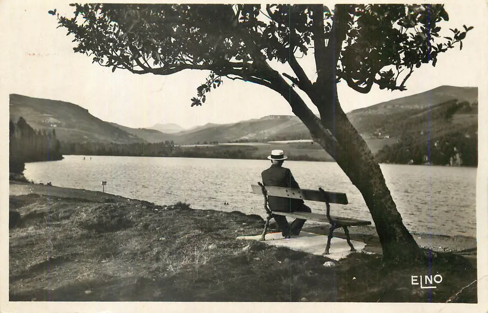 Mann sitzt auf einer Bank am See — bergiges Landschaftsbild — EILNO - Vorderseite