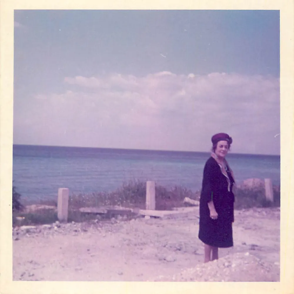 Vrouw aan de rand van de zee — zandstrand met palen — gedateerd rond 1950 - Voorkant