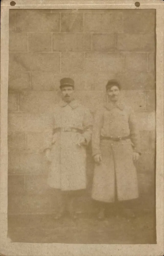 Dois homens em uniforme — em frente a um muro de pedras - Frente
