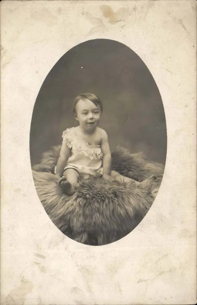 Bebê sentado sobre uma pele de animal — fotografia em preto e branco — cartão postal francês - Frente