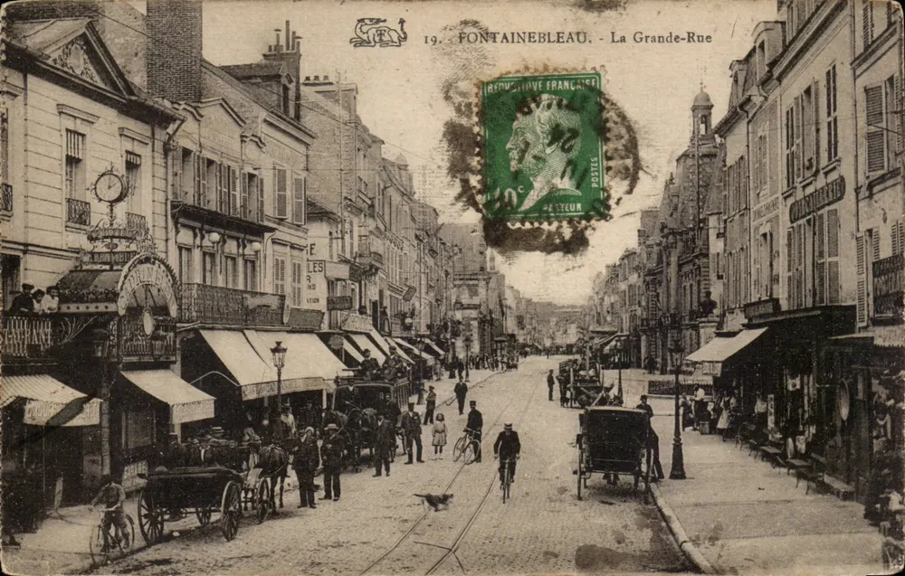 Fontainebleau - La Grande-Rue — vista de la calle comercial con peatones y vehículos — editor no identificado, número de serie 19 - Anverso