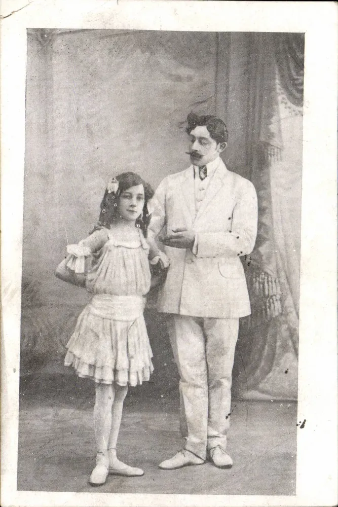 Jovem moça e homem em traje — estúdio fotográfico — datada 1910 - Frente
