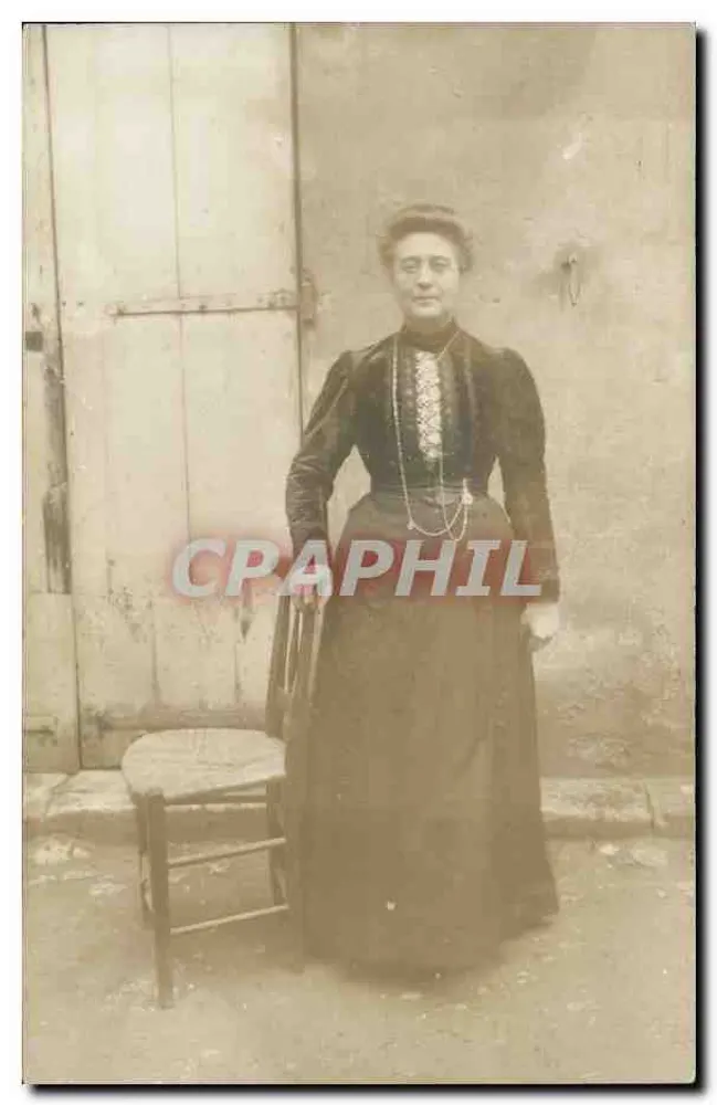 Mulher em vestido escuro — diante da porta e da cadeira — Sociedade dos Produtos 'AN DE TREFFLE' - Frente
