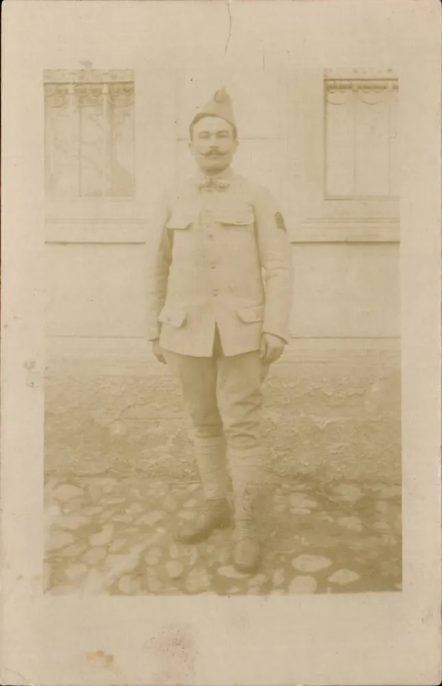 Soldat in Uniform — vor einem Gebäude posierend — Ansichtskarte - Vorderseite