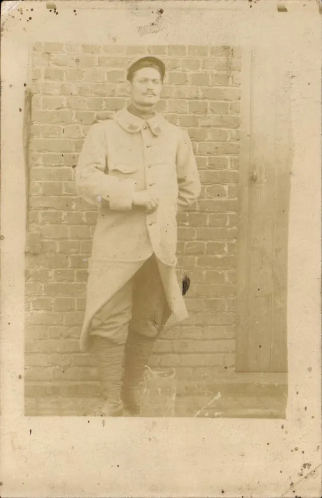 Soldat en uniforme — pose devant mur en briques — carte postale sans texte imprimé visible - Recto