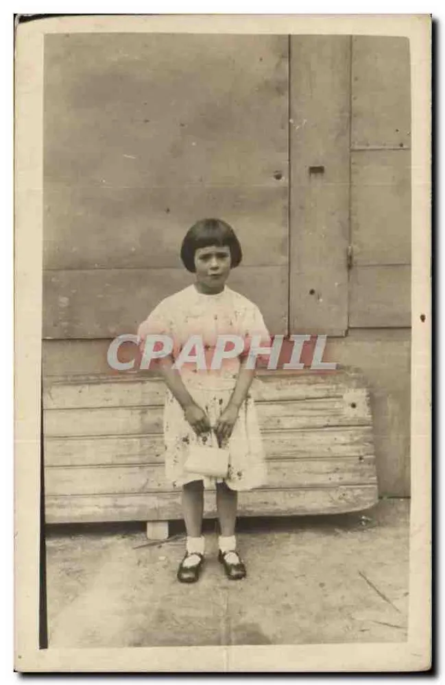 Menina com vestido estampado — diante de uma parede de madeira — carta postal anônima - Frente