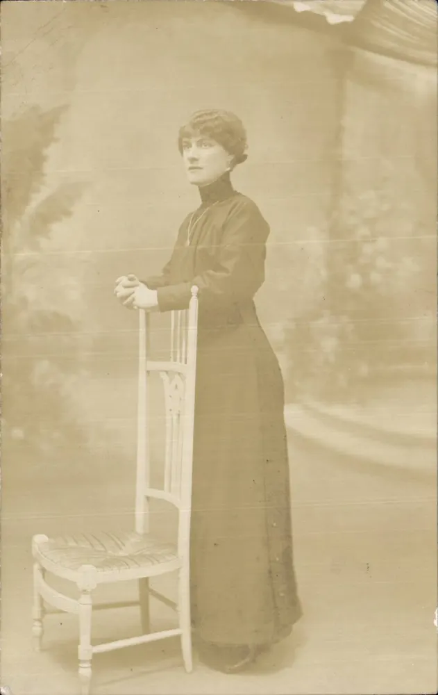 Joven mujer en vestido largo — pose con silla — editor desconocido - Anverso
