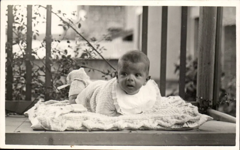 Baby auf einer Terrasse — Trägt ein gestricktes Body und ein Schürzchen — unbekannter Verlag, Seriennummer nicht sichtbar - Vorderseite