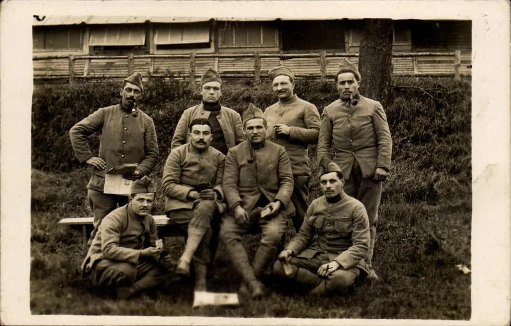 Gruppe von Soldaten — in Uniform und Mützen — vor einem Holzbau — Verlag nicht sichtbar - Vorderseite
