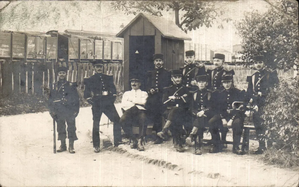 Groupe de soldats — devant un wagon de marchandises et une petite cabane — éditeur non identifié - Vorderseite