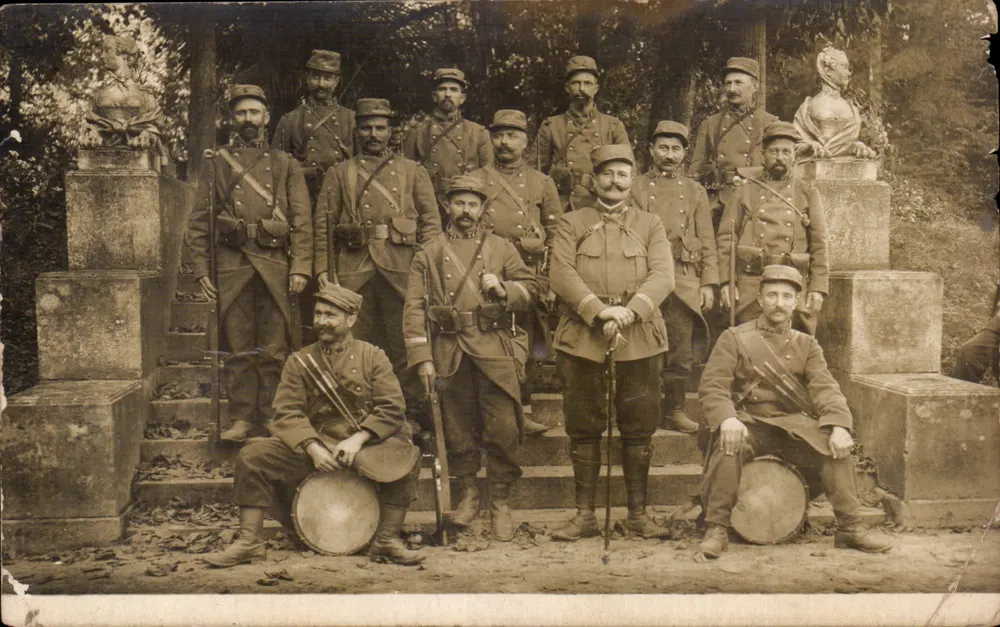 Gruppe Soldaten — in militärischer Uniform — vor Freiluftstatuen posierend - Vorderseite