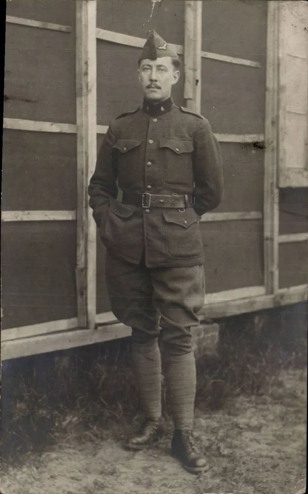 Soldat in Uniform — vor einer Holzstruktur — Ansichtskarte - Vorderseite
