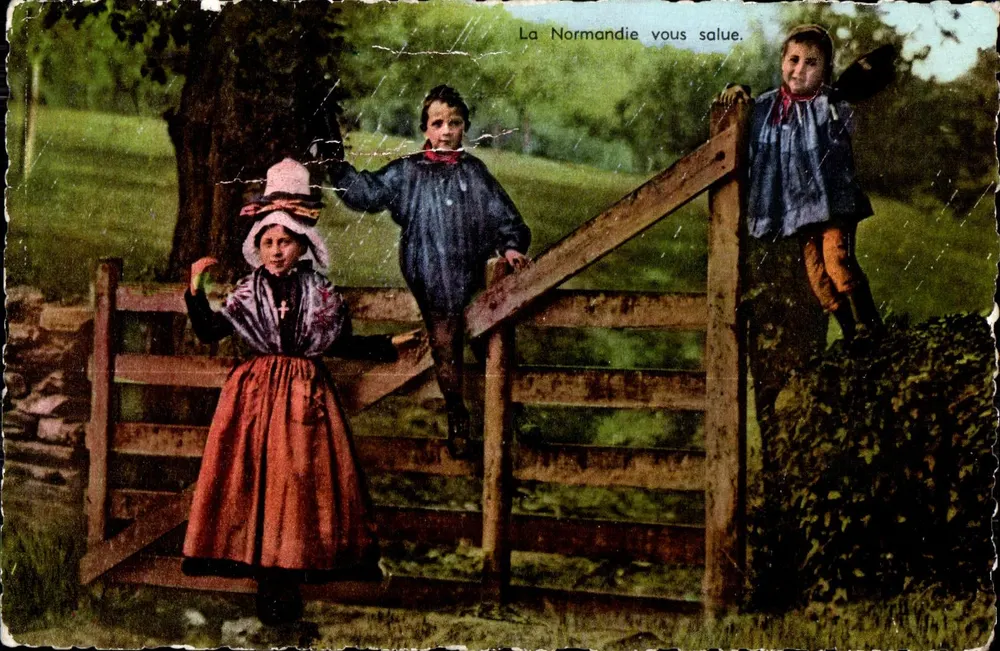Bambini e ragazza davanti a un portone — La Normandia vi saluta — Edizioni Normande Le Goubey (Manche) n°4006 - Recto
