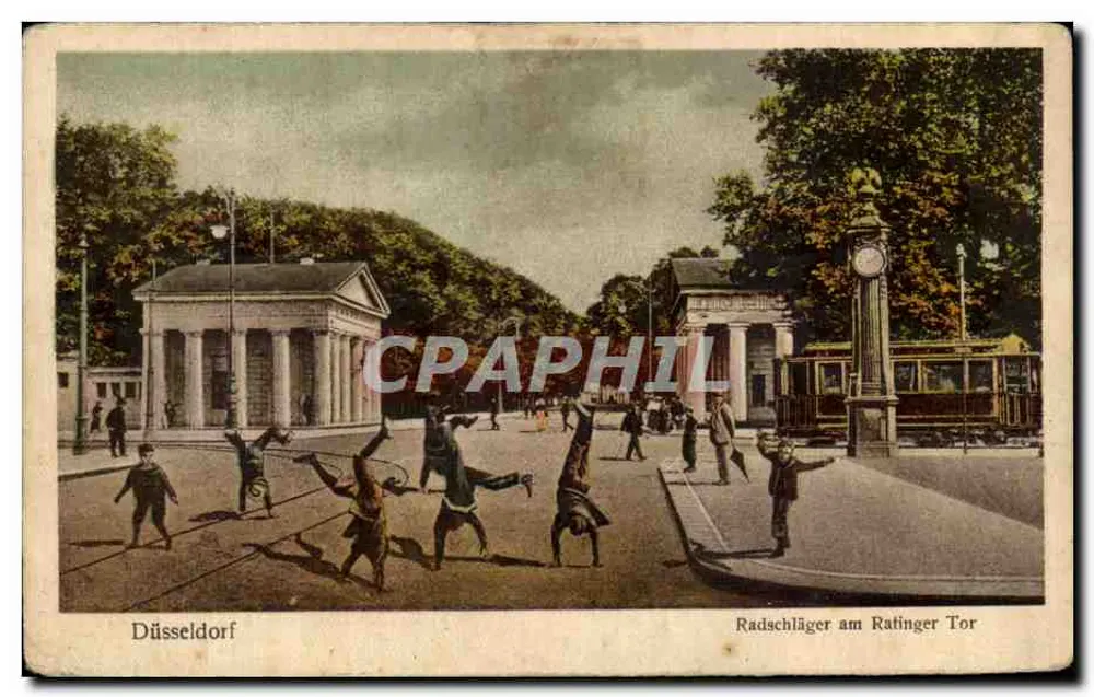 Düsseldorfer Radschlager am Ratinger Tor — scène de jeunes garçons faisant des acrobaties avec des vélos, devant un portail classique et un monument à horloge, éditeur 'Düsseldorfer Postkarten' n° 18 - Anverso