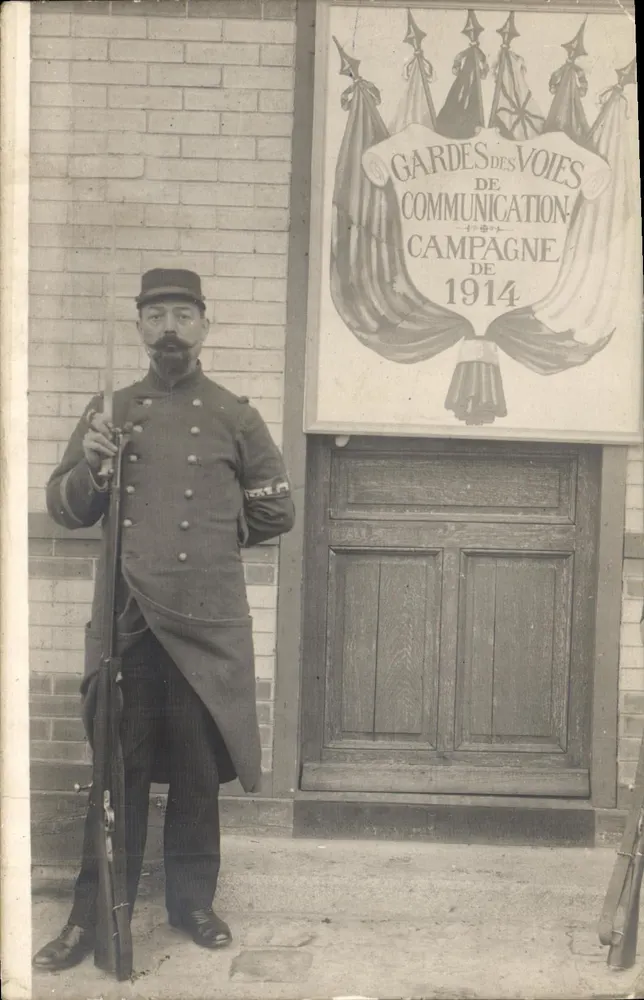 Soldat im Uniform — vor dem Plakat 'Gardes des Voies de Communication - Campagne de 1914' — Verleger nicht sichtbar - Vorderseite