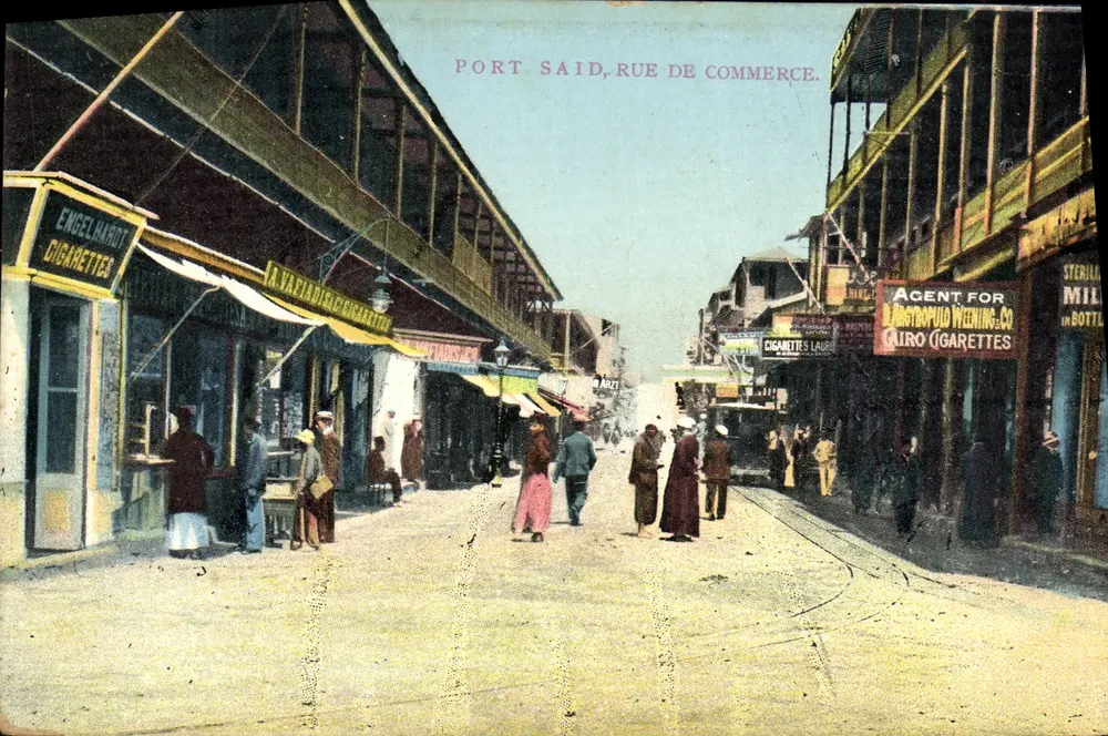 Port Said, Rue de Commerce — view de rua comercial com placas de tabacaria — The Cairo Postcard Trust, n° 457 - Frente