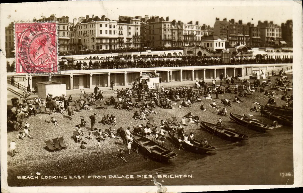 Plage vue vers l'est depuis le pont de Palais à Brighton — vue de la plage avec bateaux et promeneurs, éditeur 'Postage Revenue' et n° de série 1726 - Frente