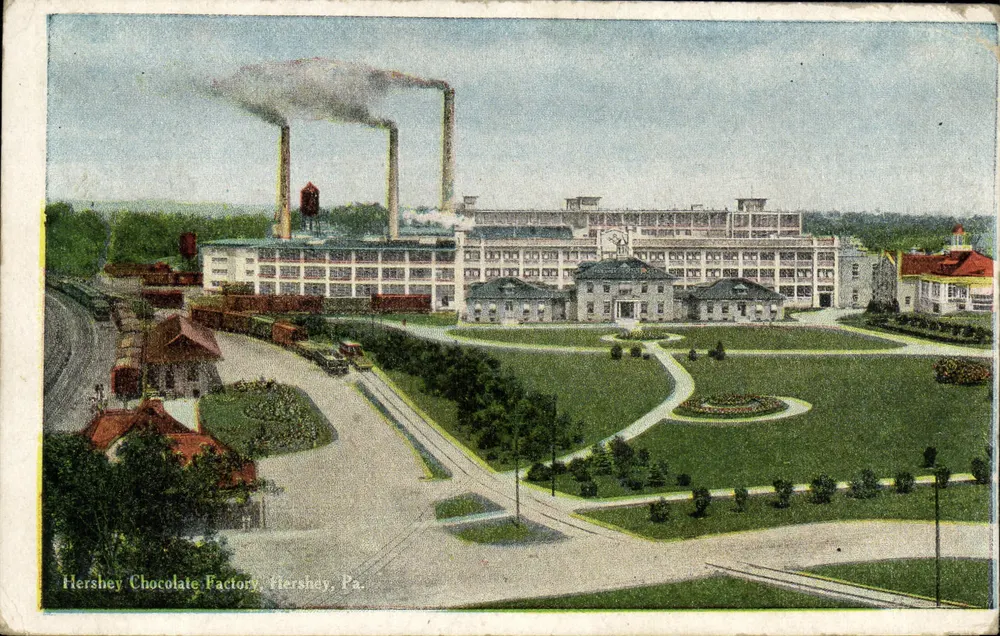 Hershey Chocolate Factory — vue de l'usine avec cheminées fumantes et jardin — éditeur non visible, n° de série non lisible - Frente