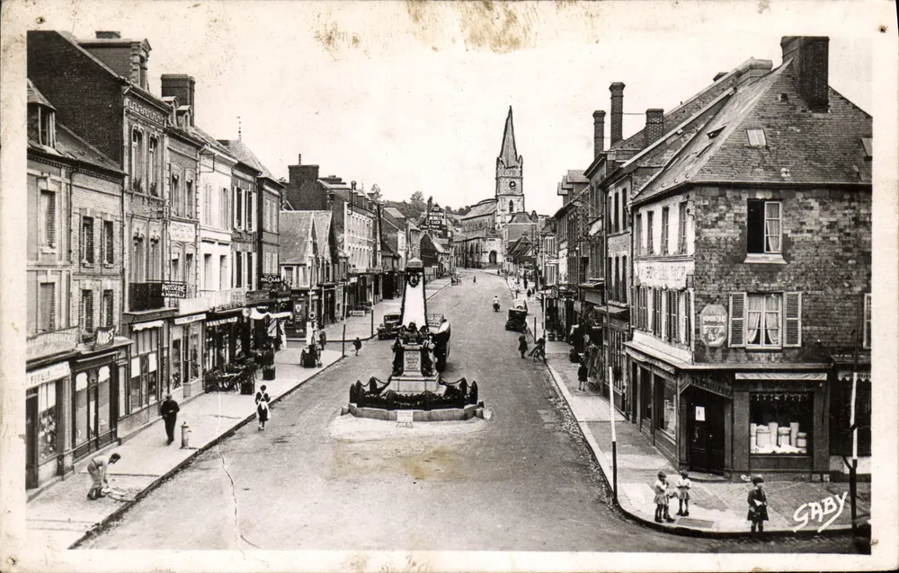 Livarot (Calvados) — rue du Maréchal Foch avec monument central et église en arrière-plan — éditeur SABY - Frente