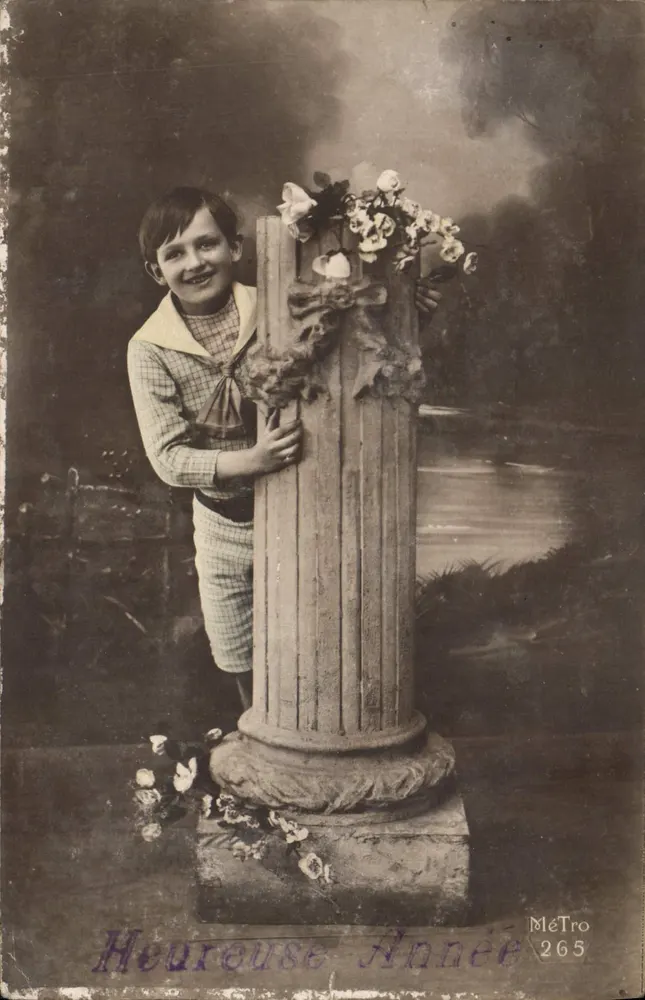 Enfant souriant — devant un pilier décoré de fleurs — MéTro 265 - Frente