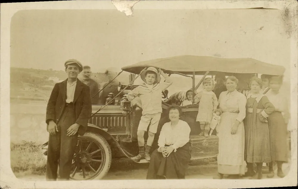 Família em frente a um automóvel antigo — número de série não visível - Frente