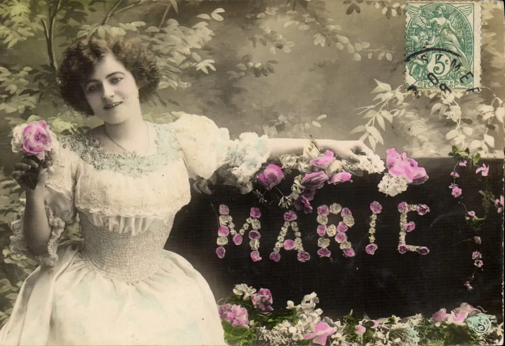 Mulher com vestido de mangas largas — decoração floral com o nome 'MARIE' — editor CROSTES, n° 5 - Frente