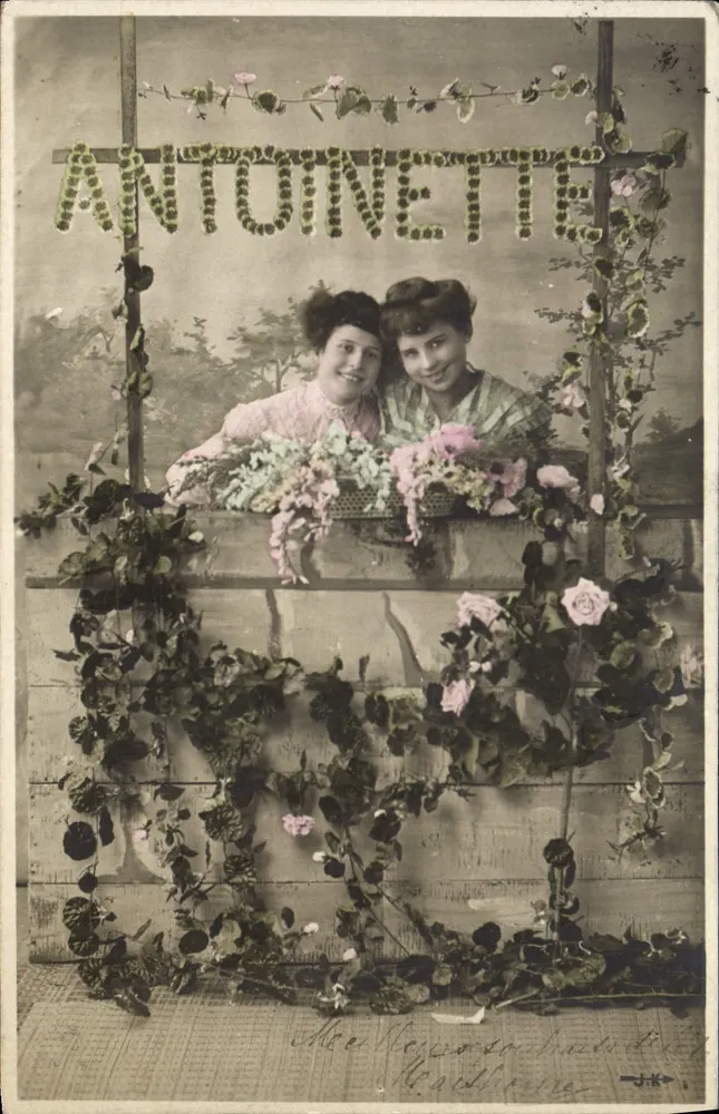 Zwei junge Frauen — vor einem blumigen Dekor mit dem Wort 'ANTOINETTE' — Verlag J.K. - Vorderseite
