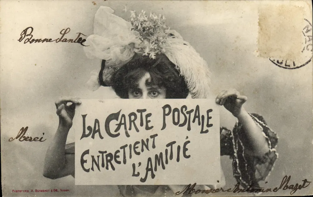 Femme en chapeau fleuri — tenant une pancarte avec l'inscription 'LA CARTE POSTALE ENTRETIEN L'AMITIÉ' — Phototypie A. BERGERET & CIE, NANCY - Vorderseite