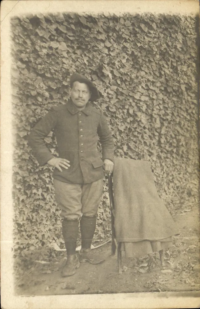 Soldat en uniforme — devant un mur couvert d'ivraie — éditeur non visible - Recto